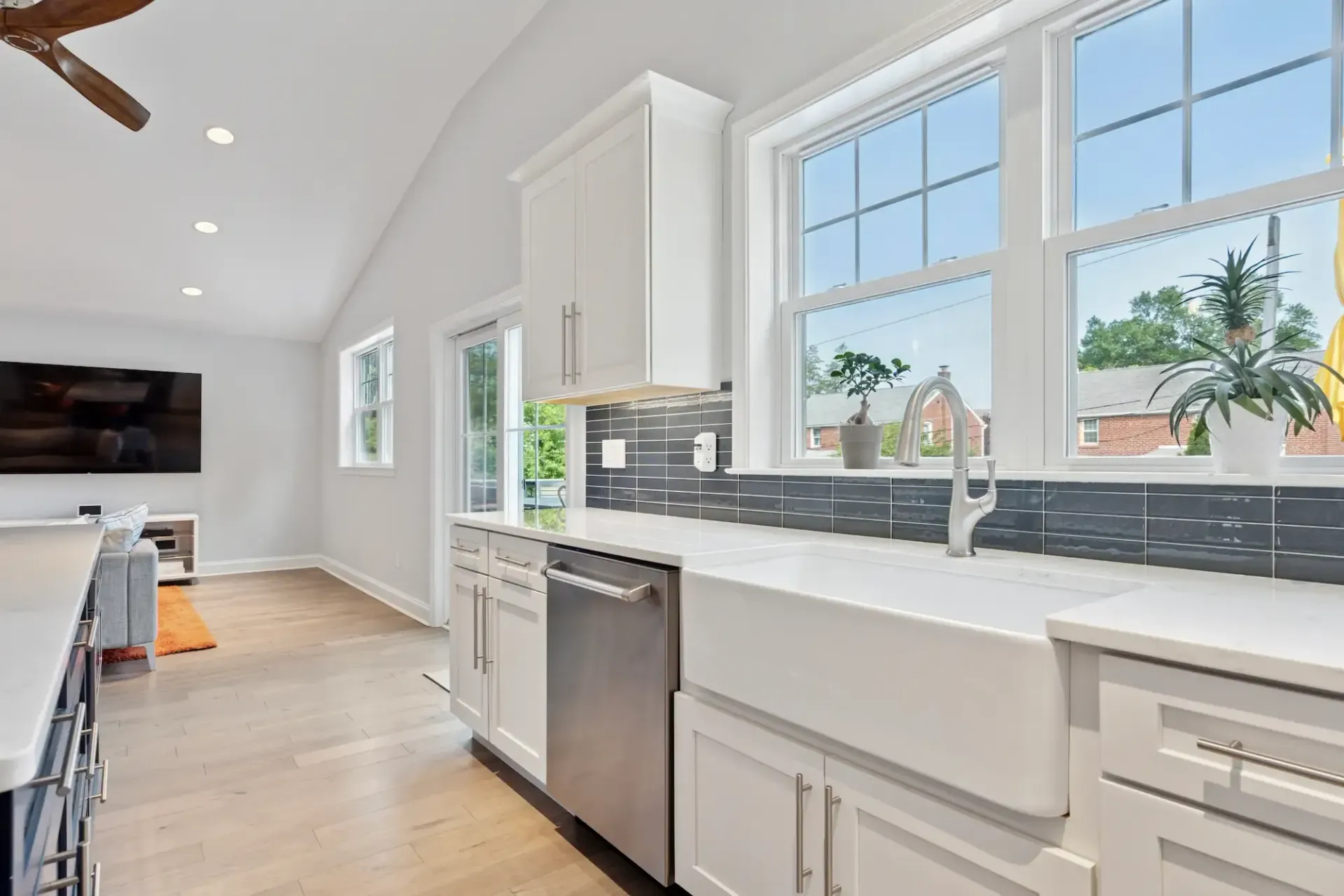 A kitchen with white cabinets , stainless steel appliances , a sink , and a ceiling fan.