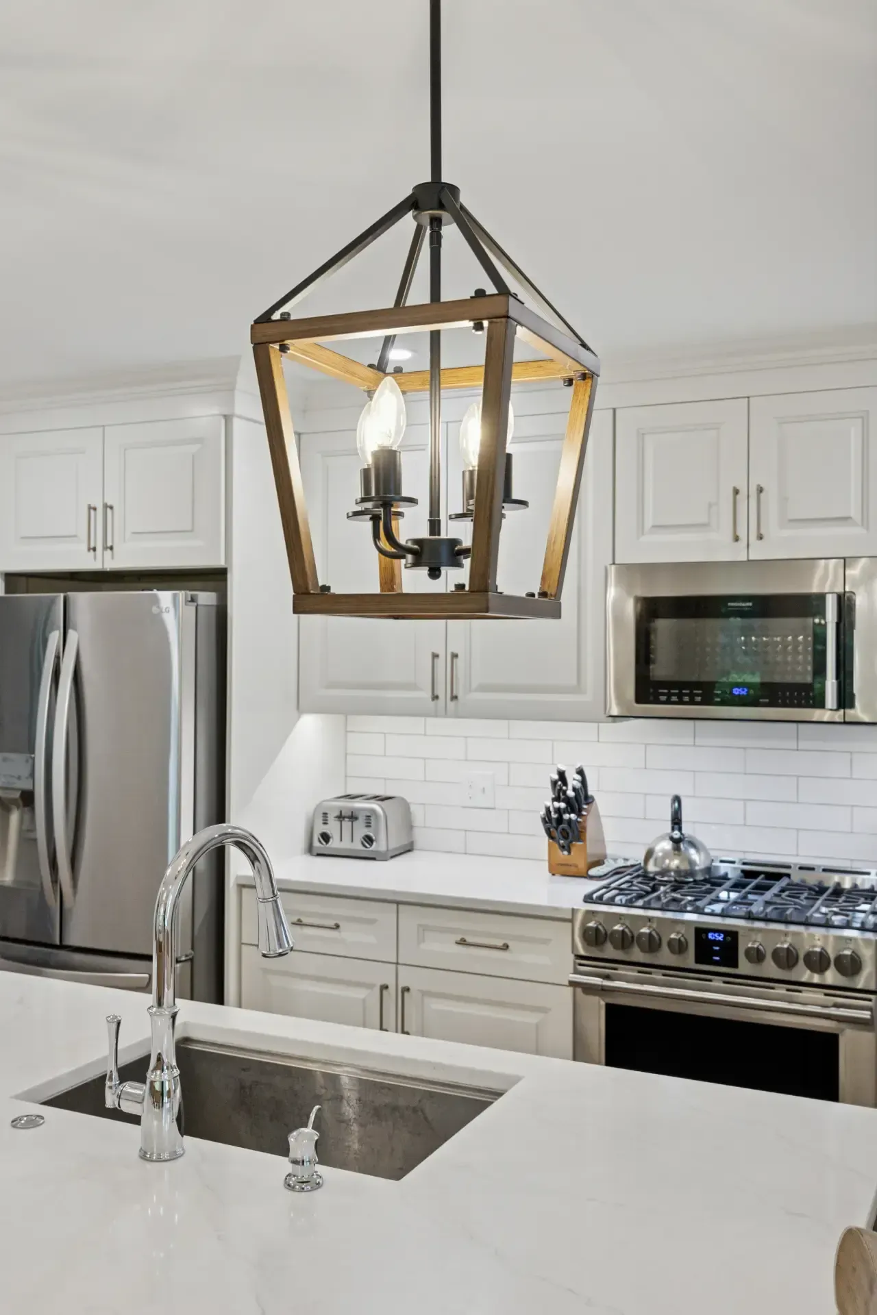 A kitchen with a sink , stove , refrigerator and microwave.