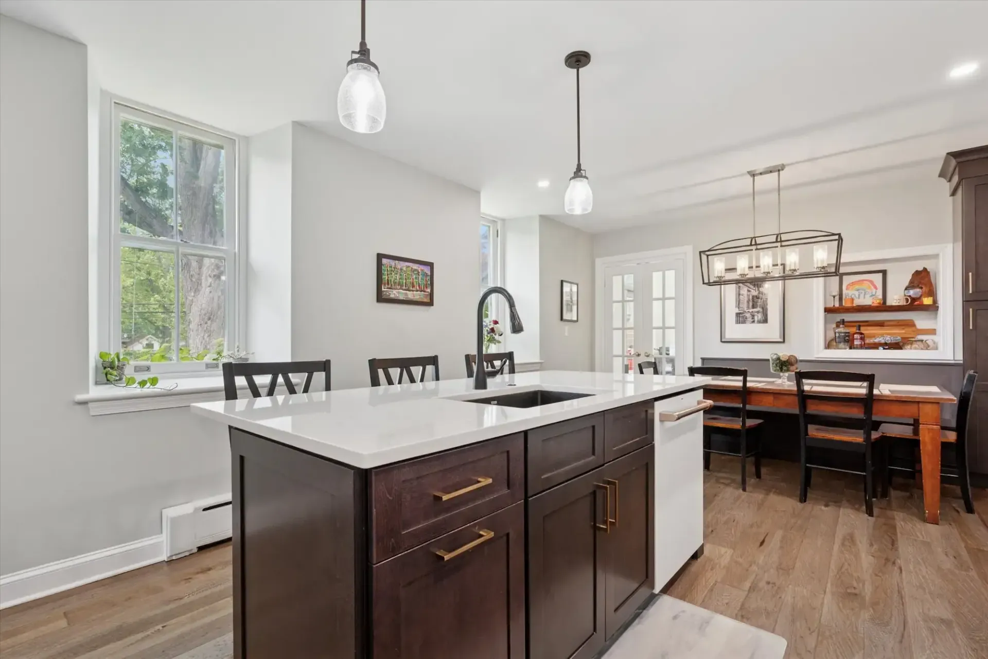 A kitchen with a large island , sink , dining table and chairs.