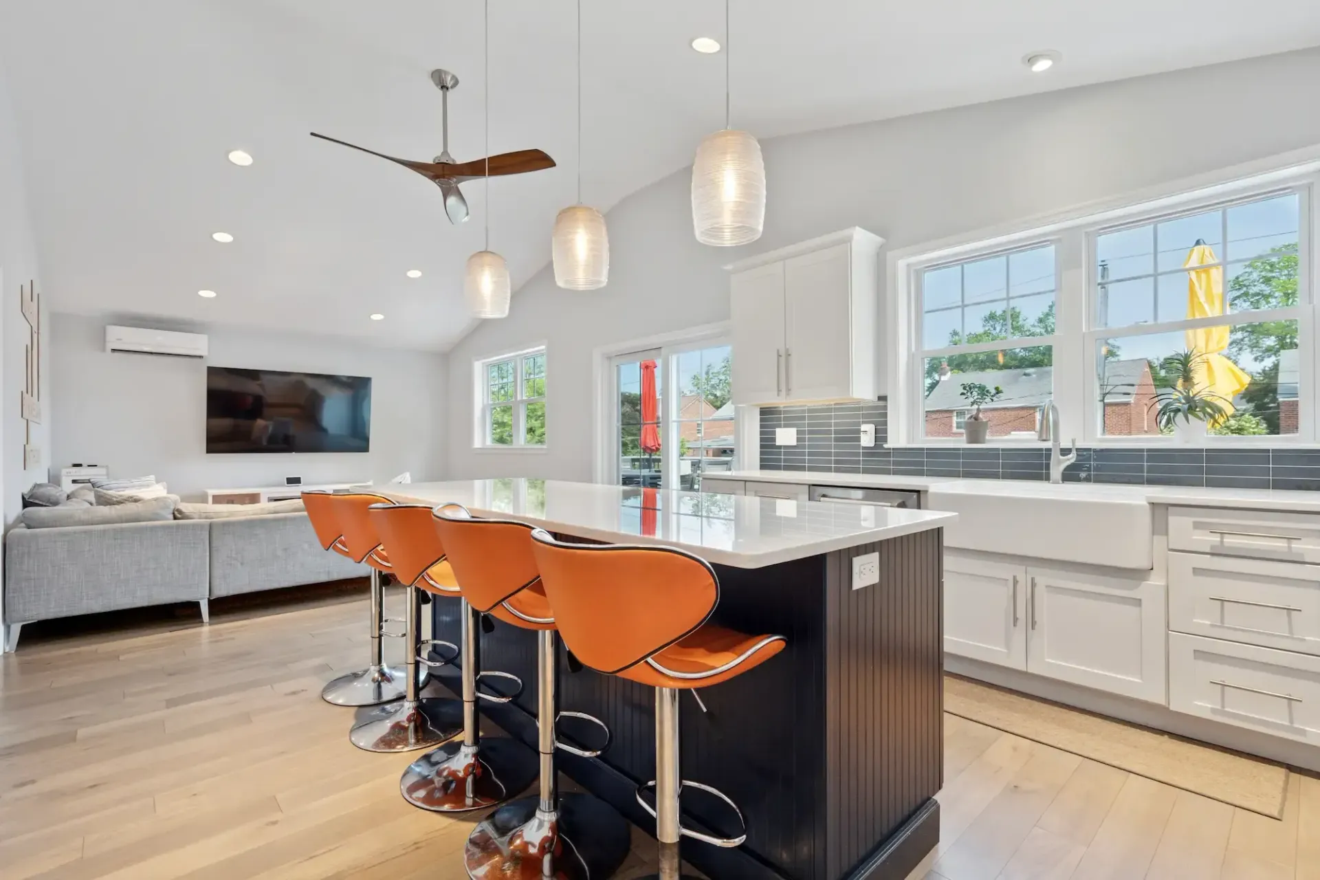 A kitchen with a large island , stools and a ceiling fan.