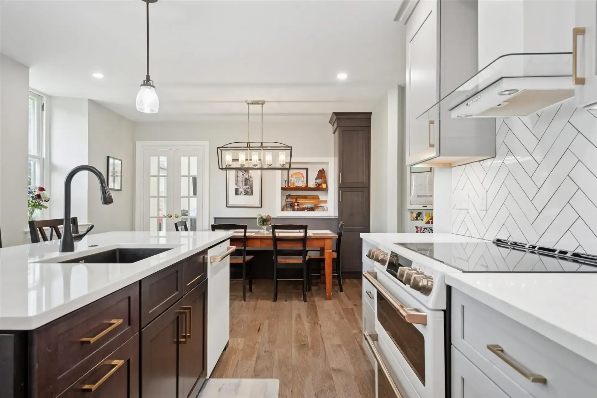 A kitchen with white cabinets , a sink , a stove , and a table.
