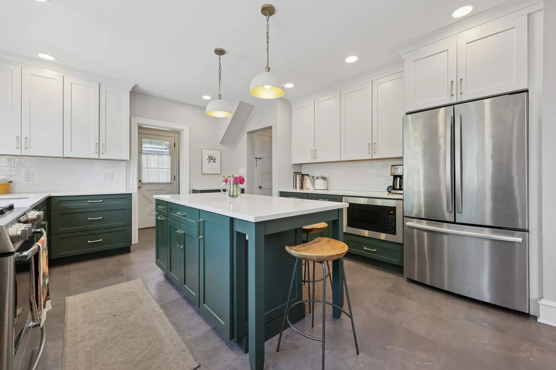 A kitchen with white cabinets , stainless steel appliances , a large island , and a refrigerator.