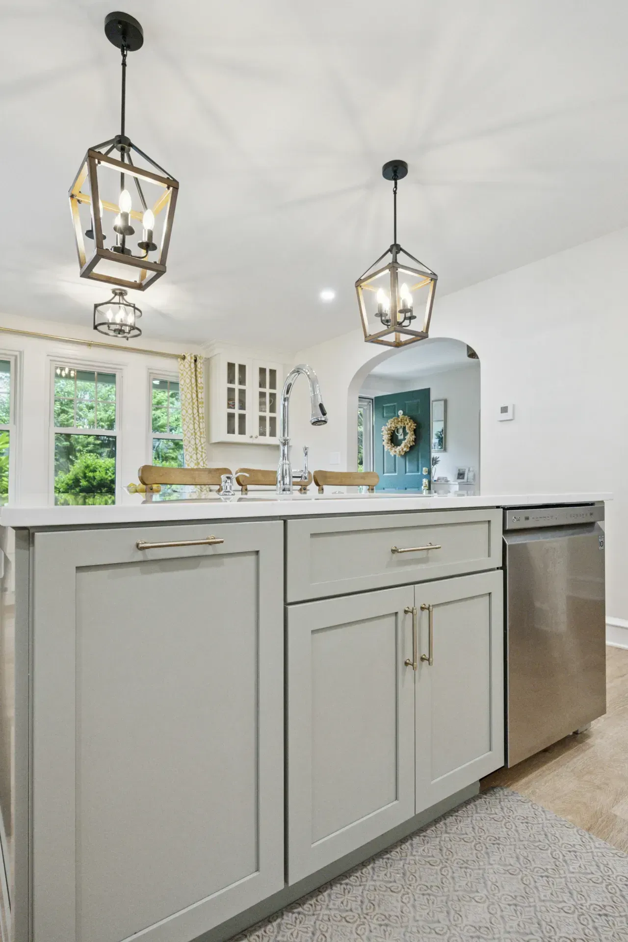A kitchen with white cabinets , a sink , and a stainless steel dishwasher.