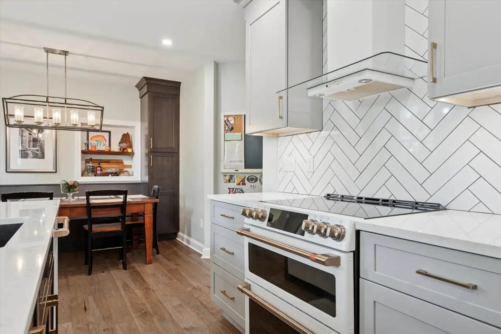A kitchen with white cabinets , a stove , a table and chairs.
