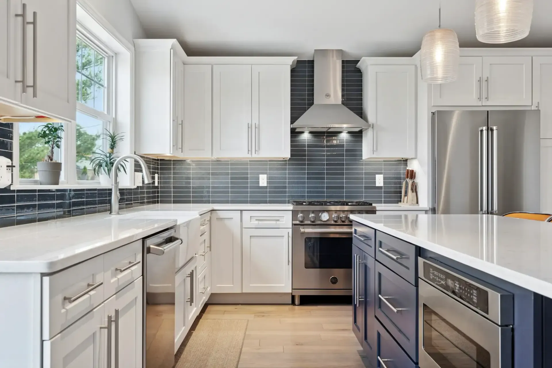 A kitchen with white cabinets , blue cabinets , stainless steel appliances , and a large island.