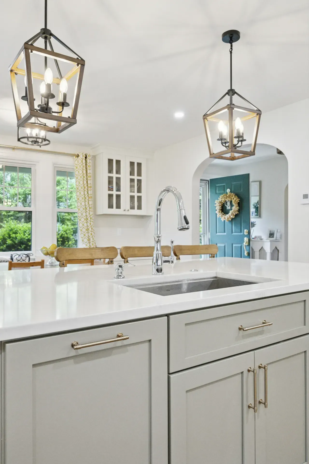 A kitchen with white cabinets , a sink , and two lanterns hanging from the ceiling.