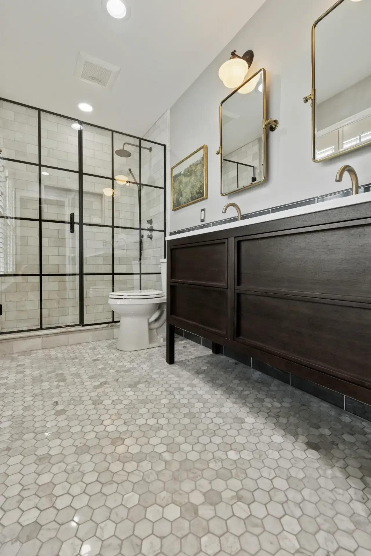A bathroom with a toilet , sink , mirror and shower stall.