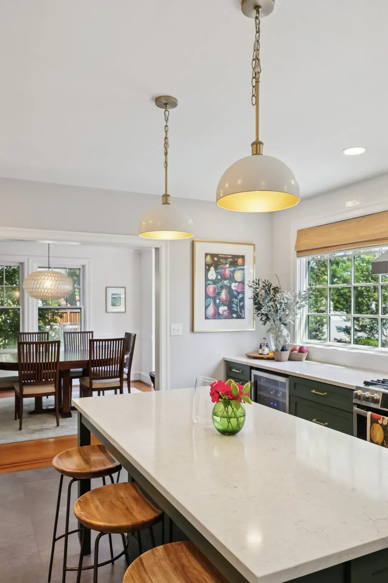 A kitchen with a large island and stools and a dining room in the background.