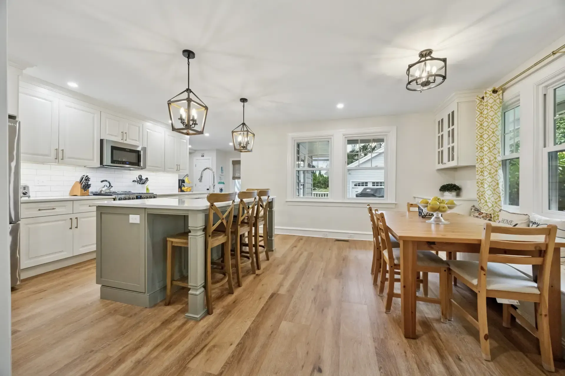 A kitchen and dining room in a house with hardwood floors and white cabinets.