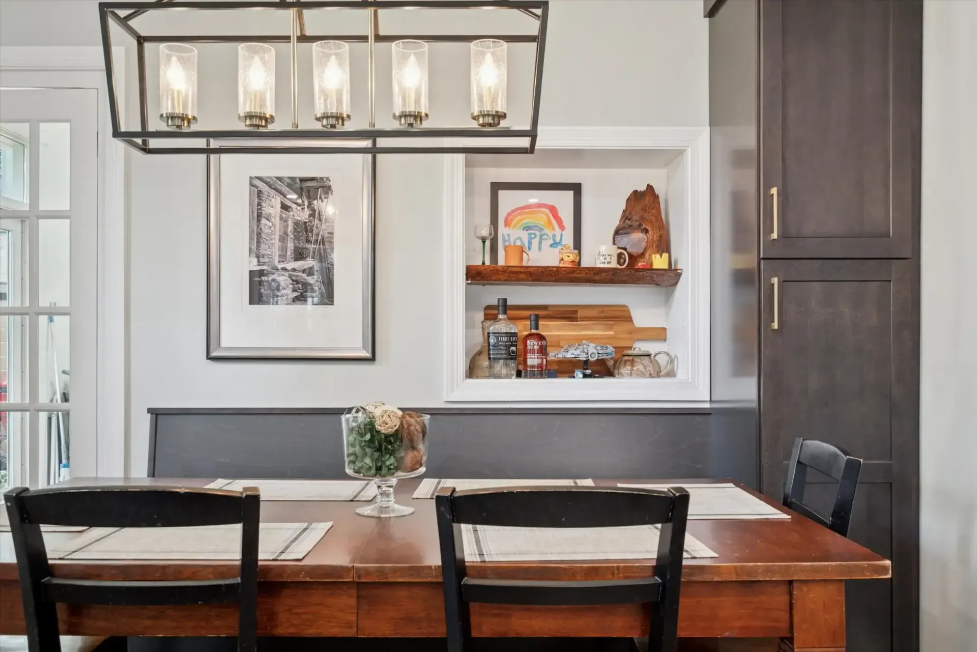 A dining room with a wooden table and chairs and a chandelier.