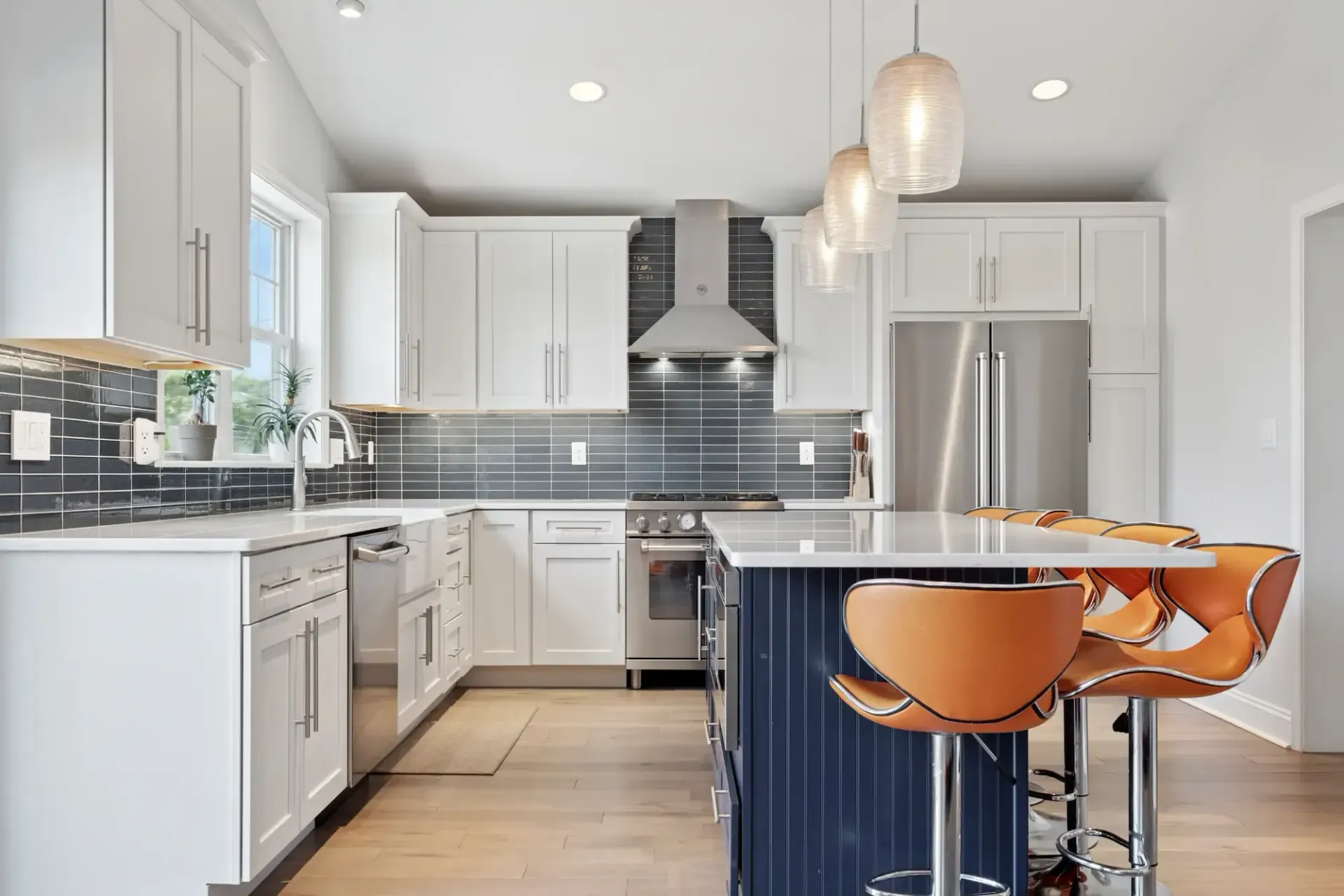 A kitchen with white cabinets , stainless steel appliances , and a blue island.