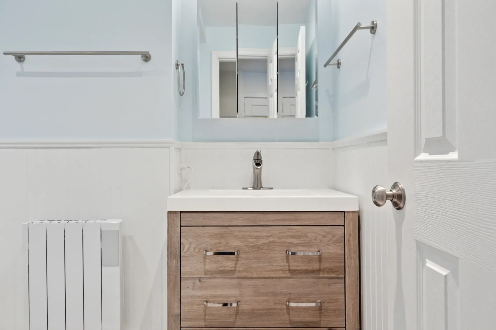 A bathroom with a sink , mirror and radiator.