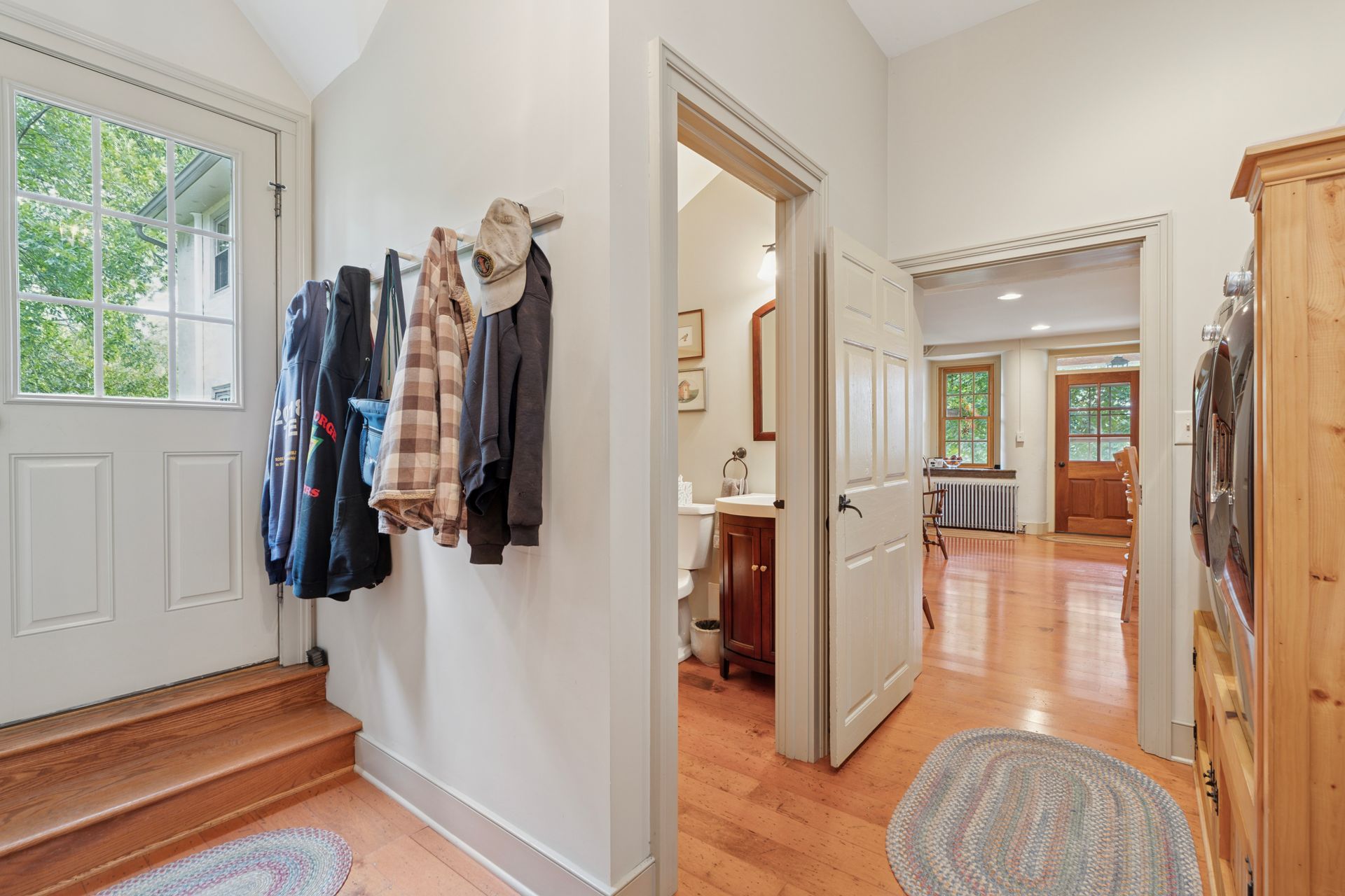 Patio with table and colorful Adirondack chairs, stone wall, and green lawn.