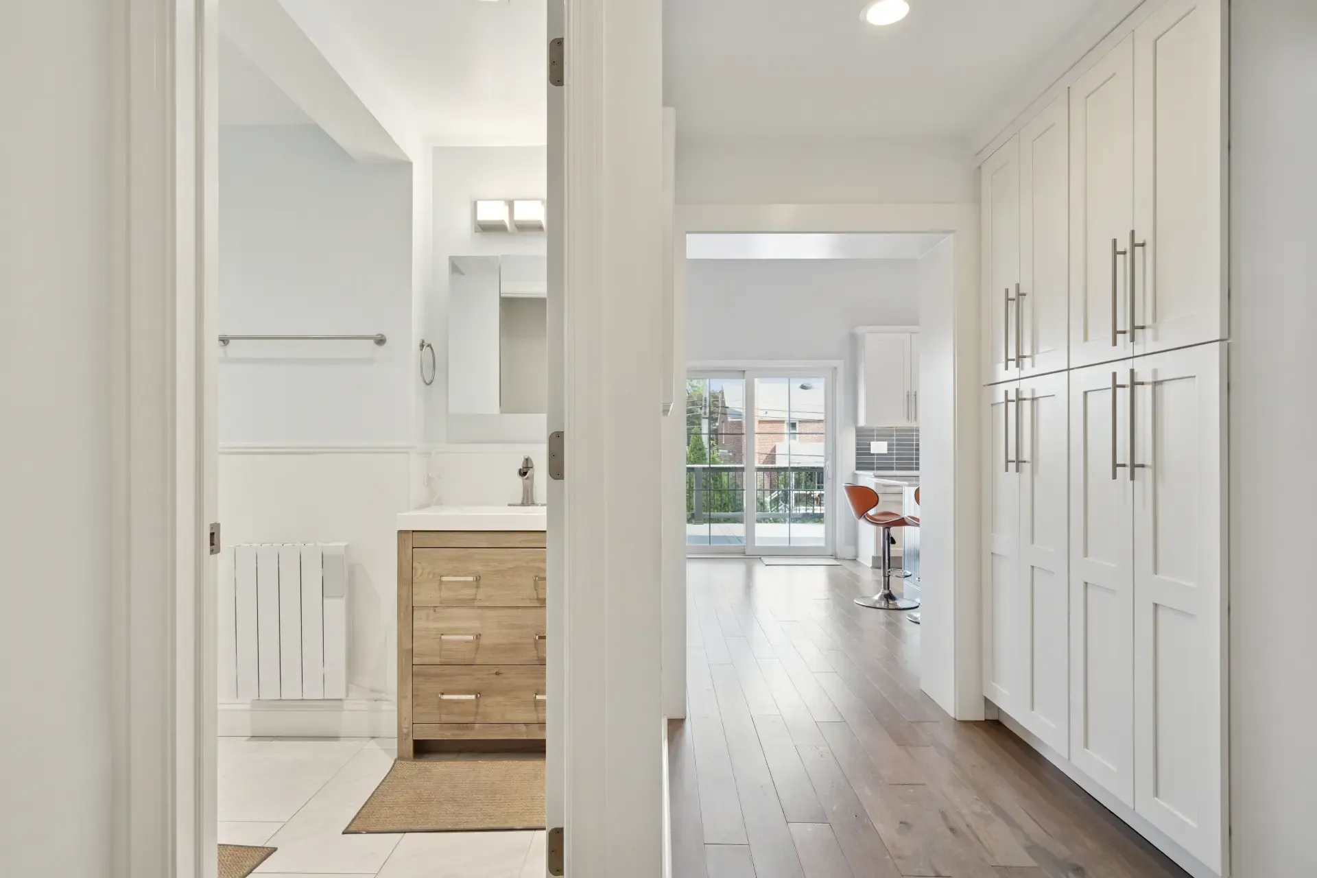 A hallway in a house leading to a bathroom and kitchen