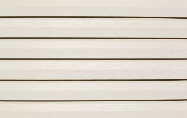 Hand writing in notebook with calculator and cash on a white table.