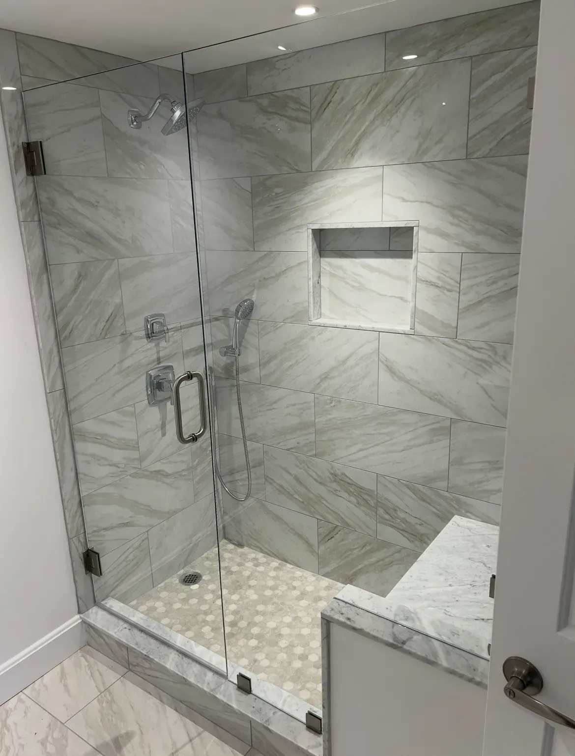 A bathroom with a walk in shower with a glass door.