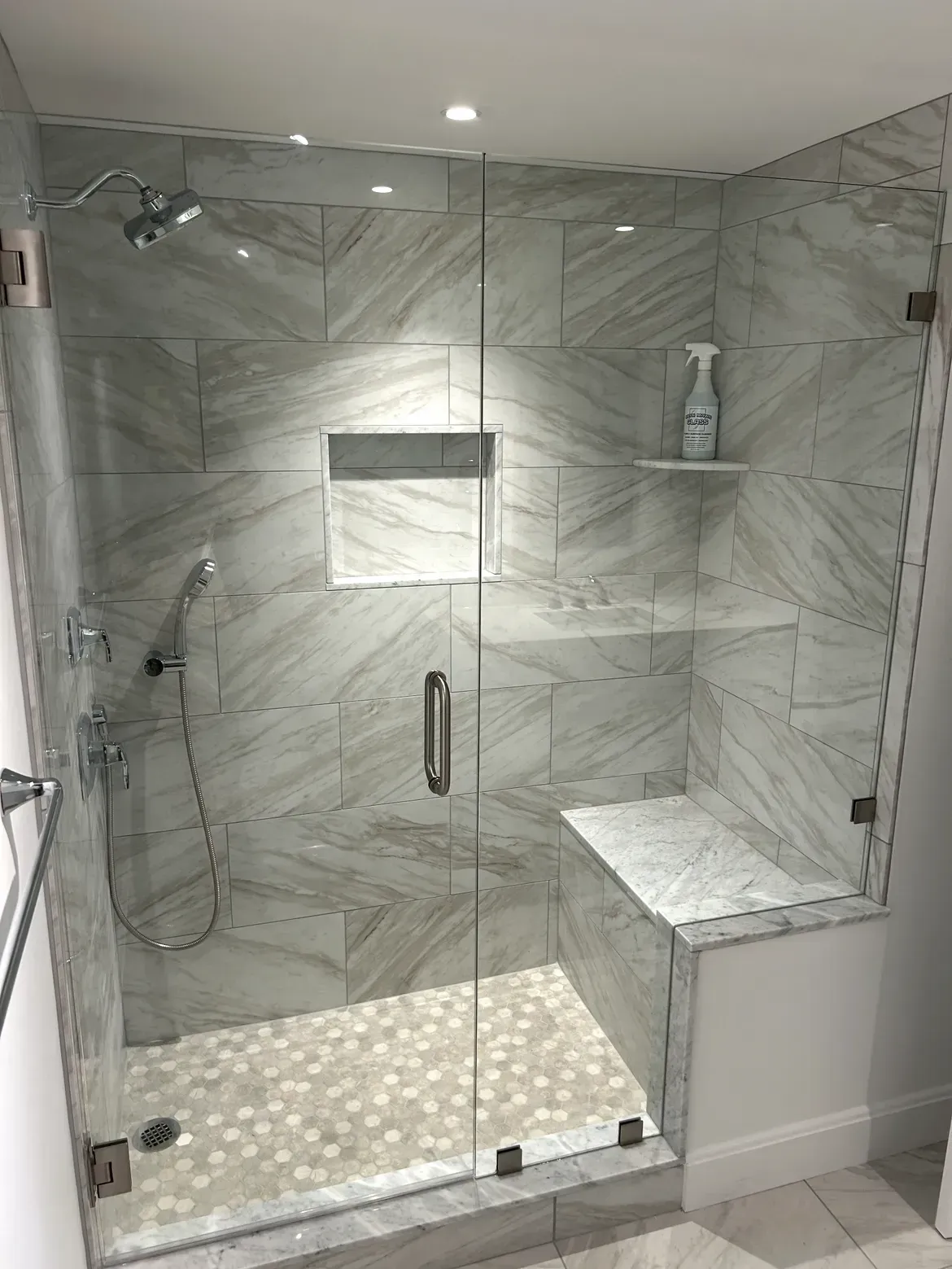 A bathroom with a walk in shower with a glass door.