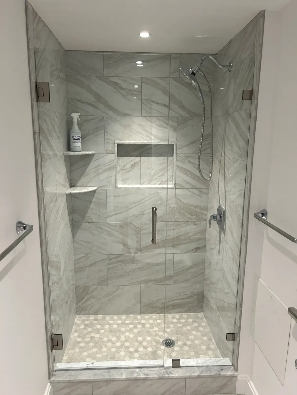 A bathroom with a walk in shower with a glass door.