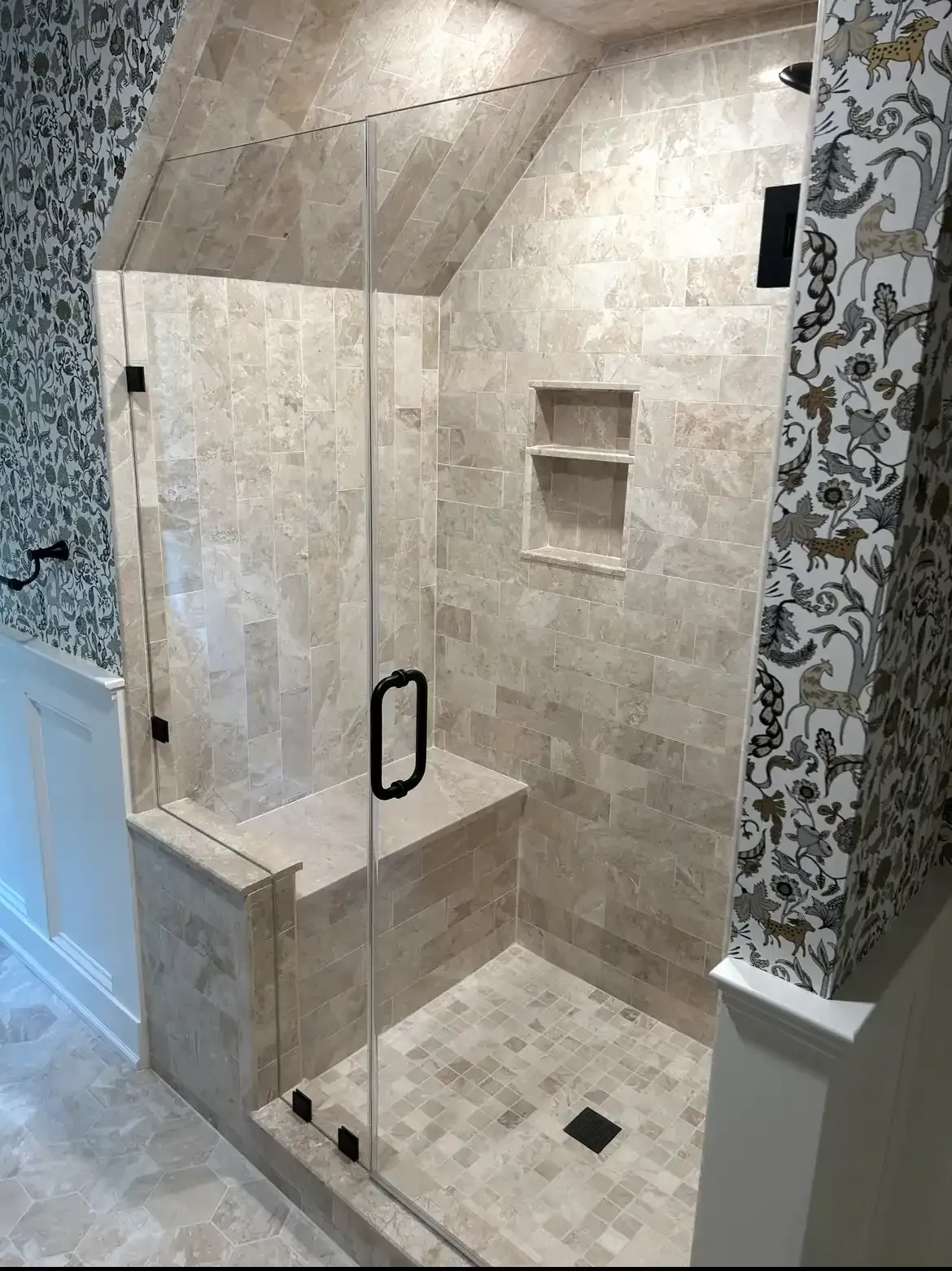 A bathroom with a walk in shower with a glass door.