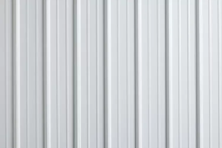 Hand writing in notebook with calculator and cash on a white table.