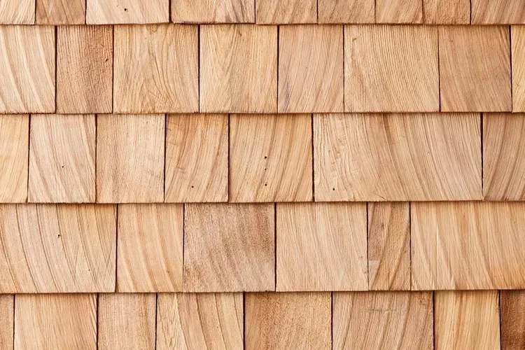 Hand writing in notebook with calculator and cash on a white table.