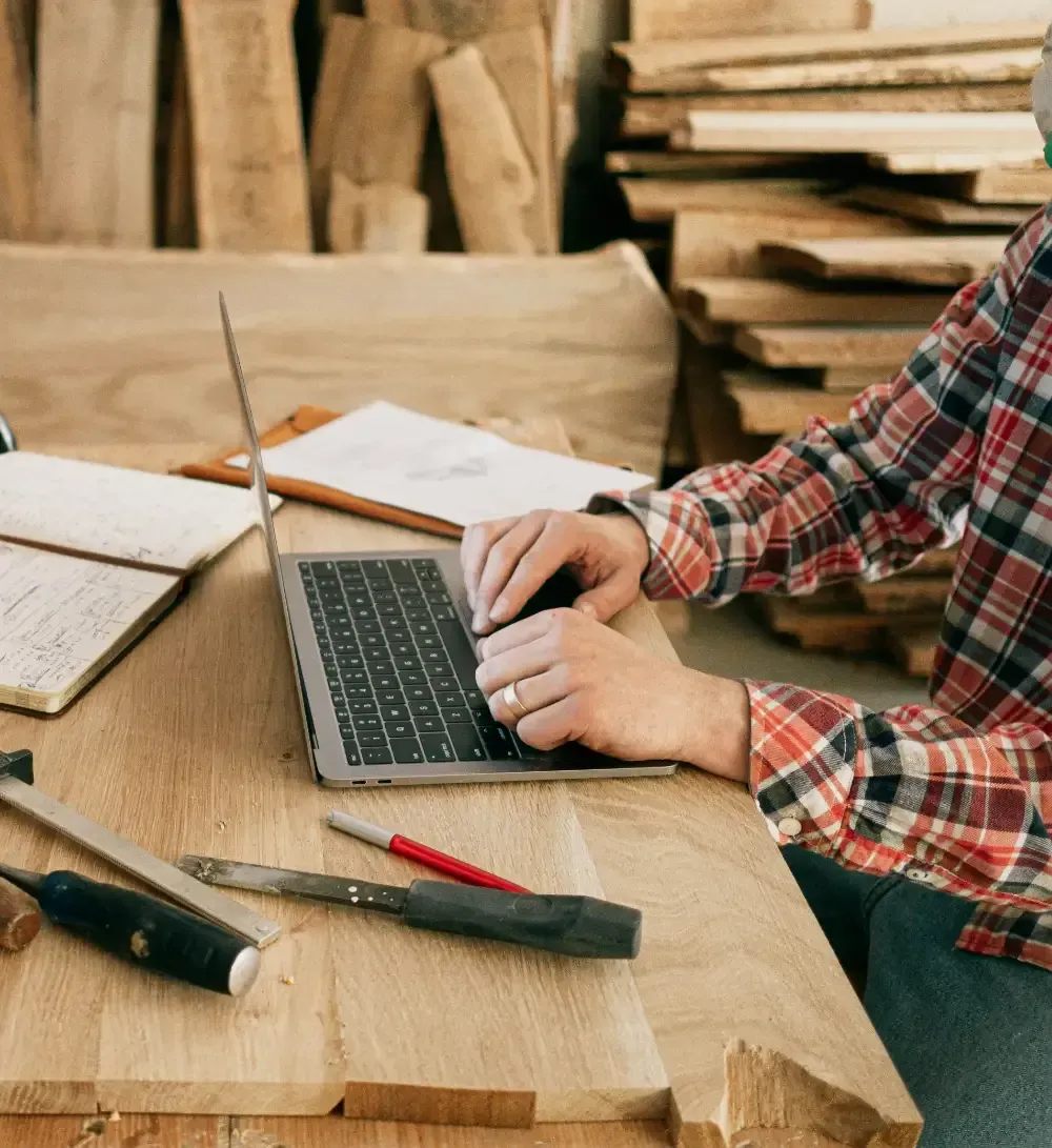 Hand writing in notebook with calculator and cash on a white table.