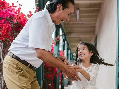 A happy man and a little girl dancing on a porch.