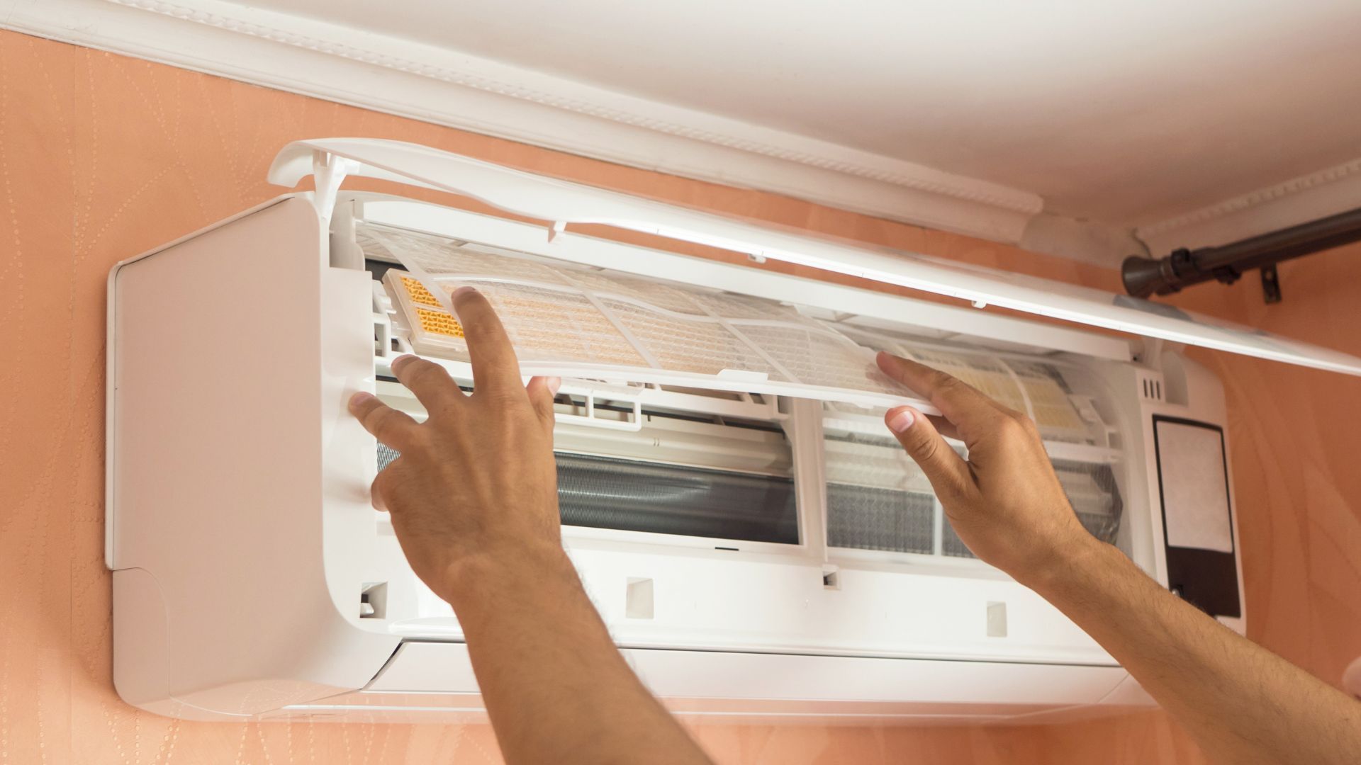 Person cleaning an air conditioner filter indoors.