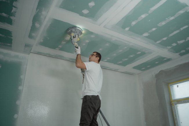 Pro interior painter polishing the ceiling in preparation for house painting project in a residential property in Hobart TAS.