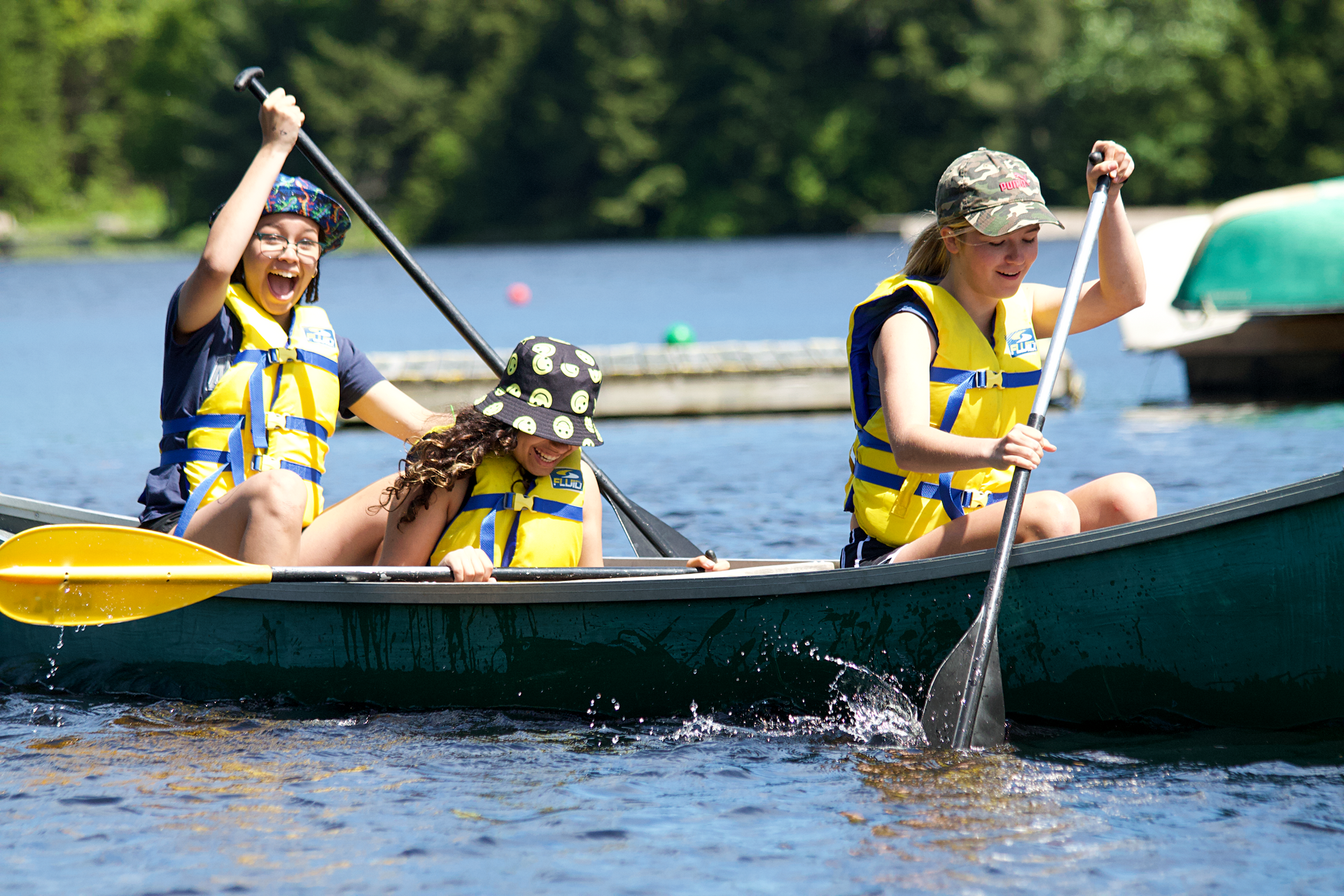 3 girls in a canoe on a lake
