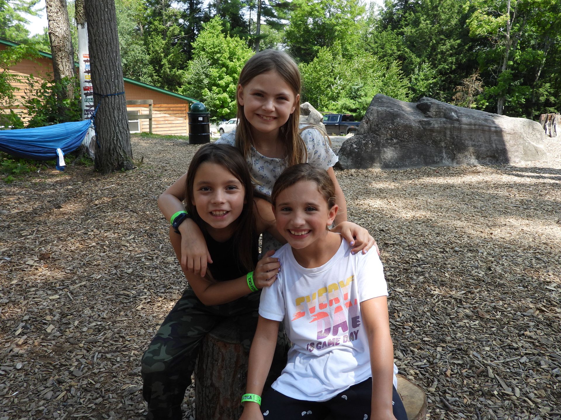 Three young girls are posing for a picture in a park