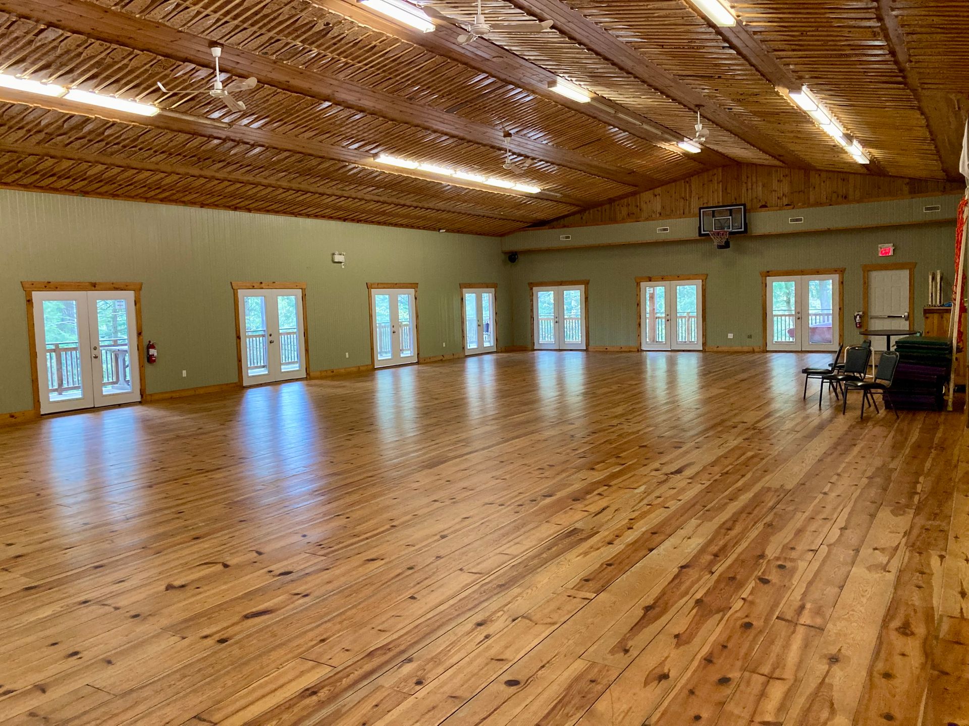 A large room with wooden floors and lots of windows.
