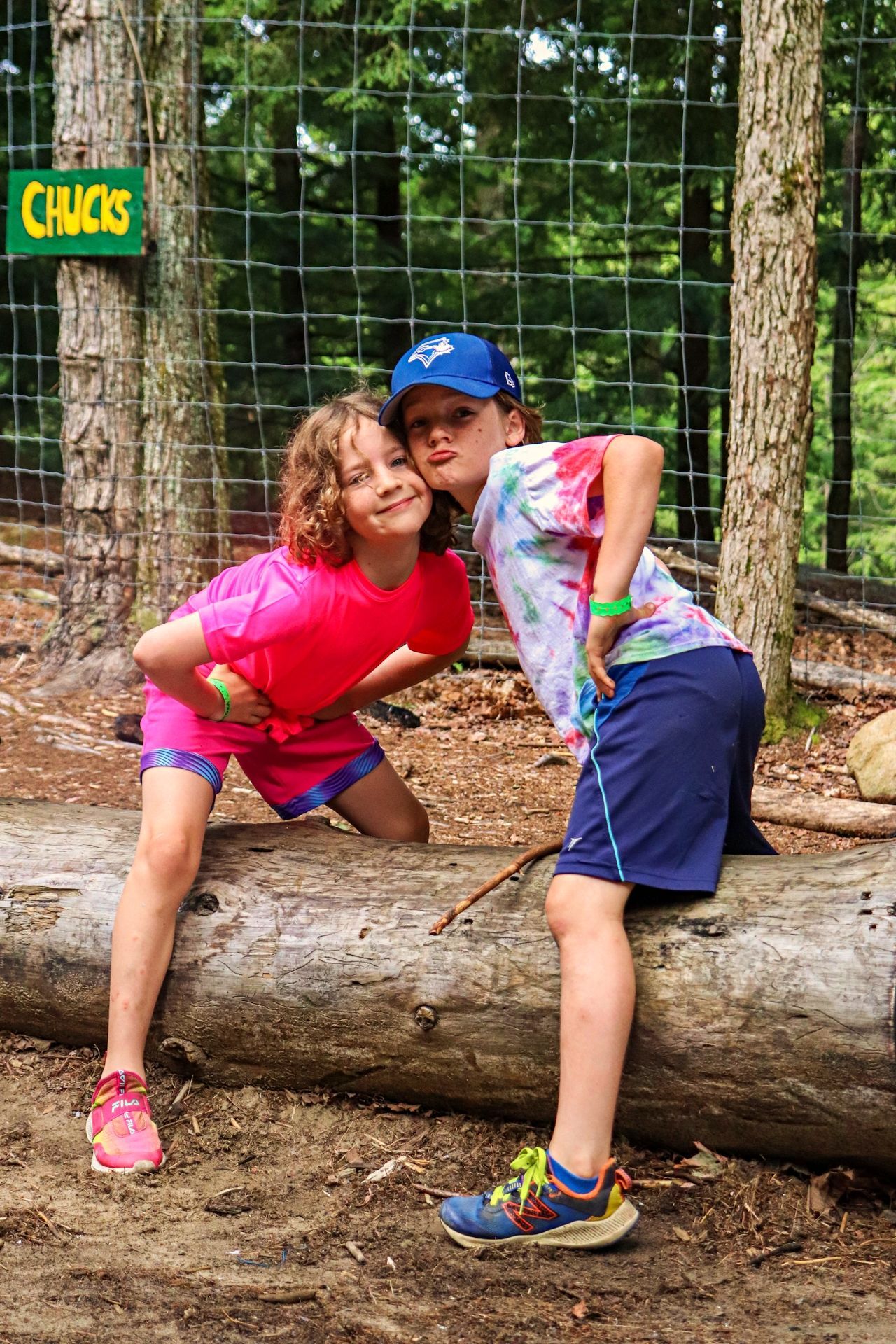 A boy and a girl are standing next to each other on a log.