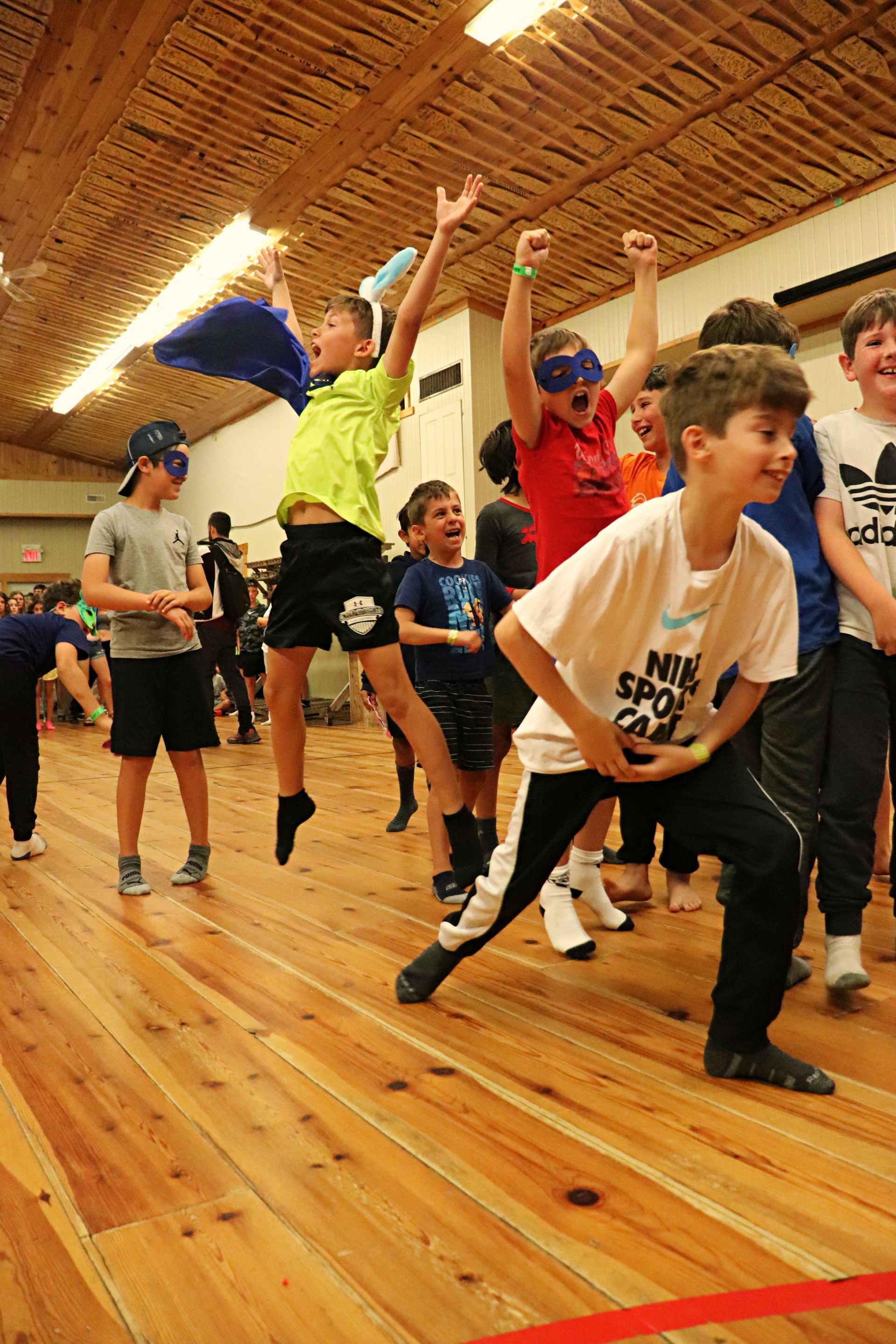 A group of young boys are jumping in the air in a gym.