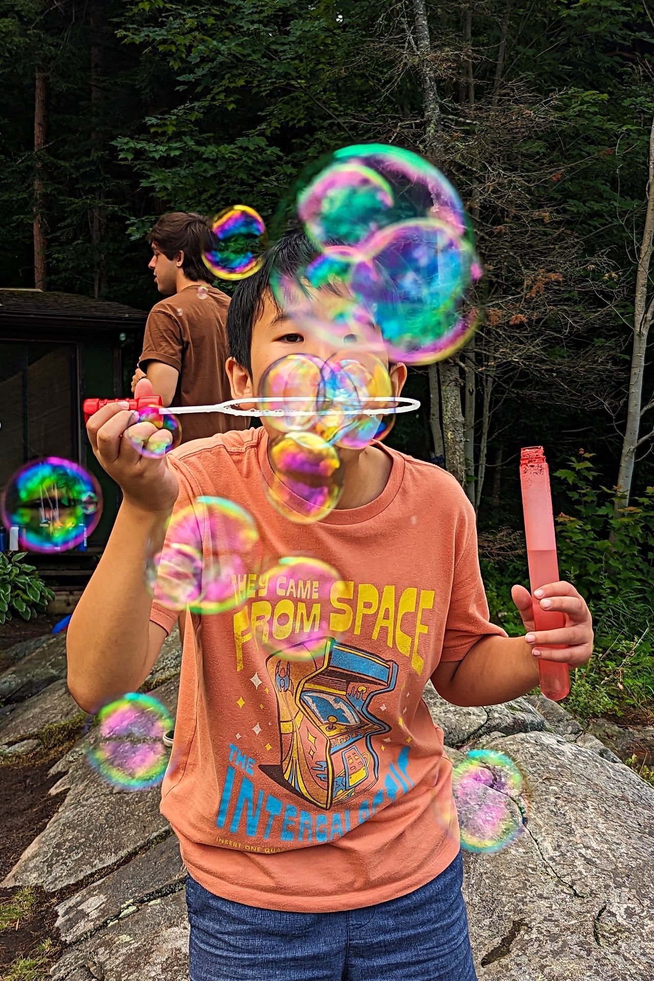 A young boy is blowing soap bubbles outside.