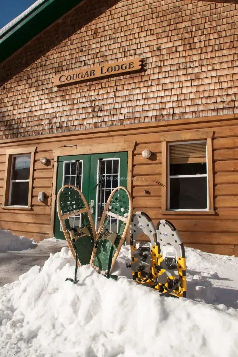 Two snowshoes are sitting in the snow in front of a coyote lodge