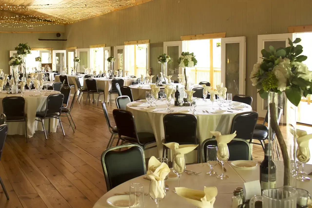 A large room with tables and chairs set up for a wedding reception