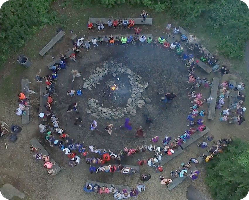 A large group of people are gathered around a fire pit