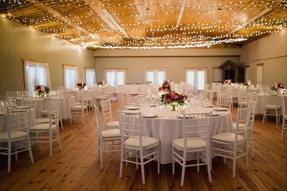 A large room with tables and chairs set up for a wedding reception.
