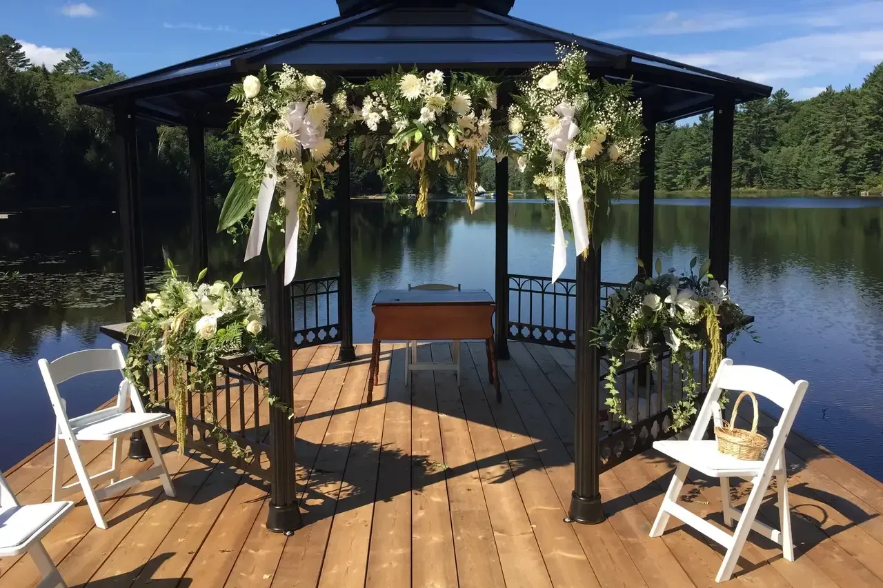 A gazebo is sitting on a wooden dock next to a lake.