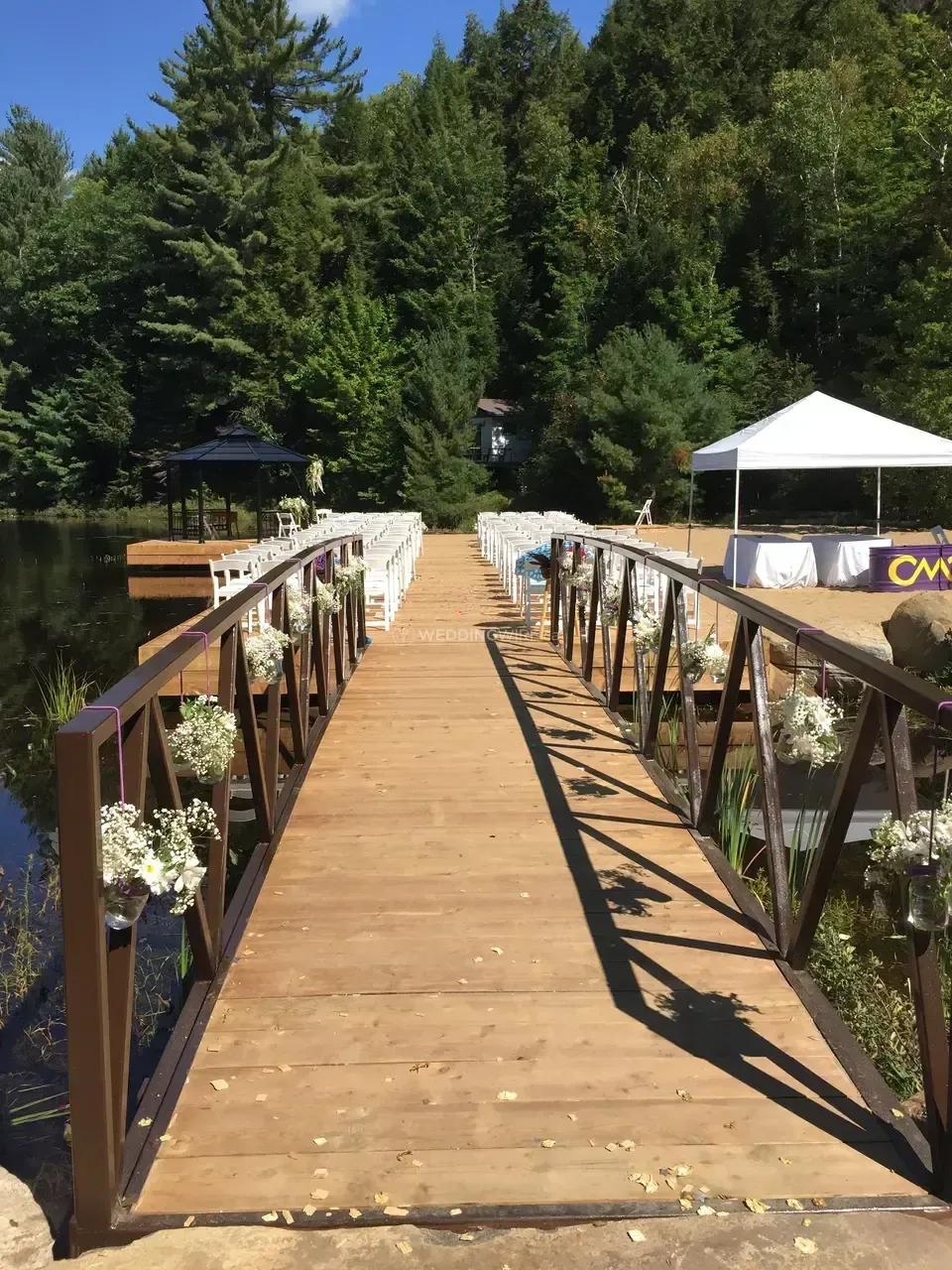 A wooden bridge over a body of water with flowers on the railing.