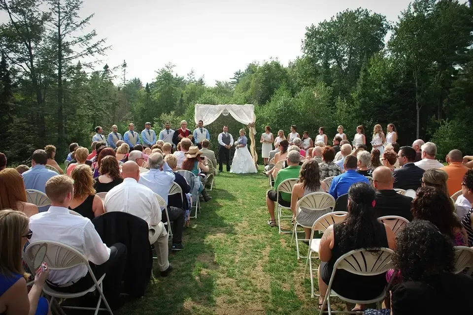 A large group of people are sitting in folding chairs at a wedding ceremony.