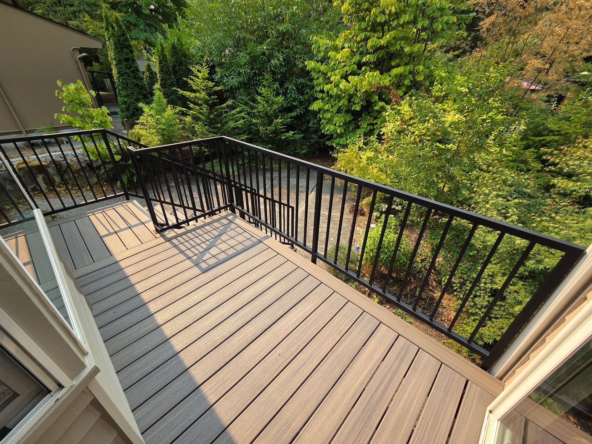 Deck with black railing overlooking a green, tree-filled yard.