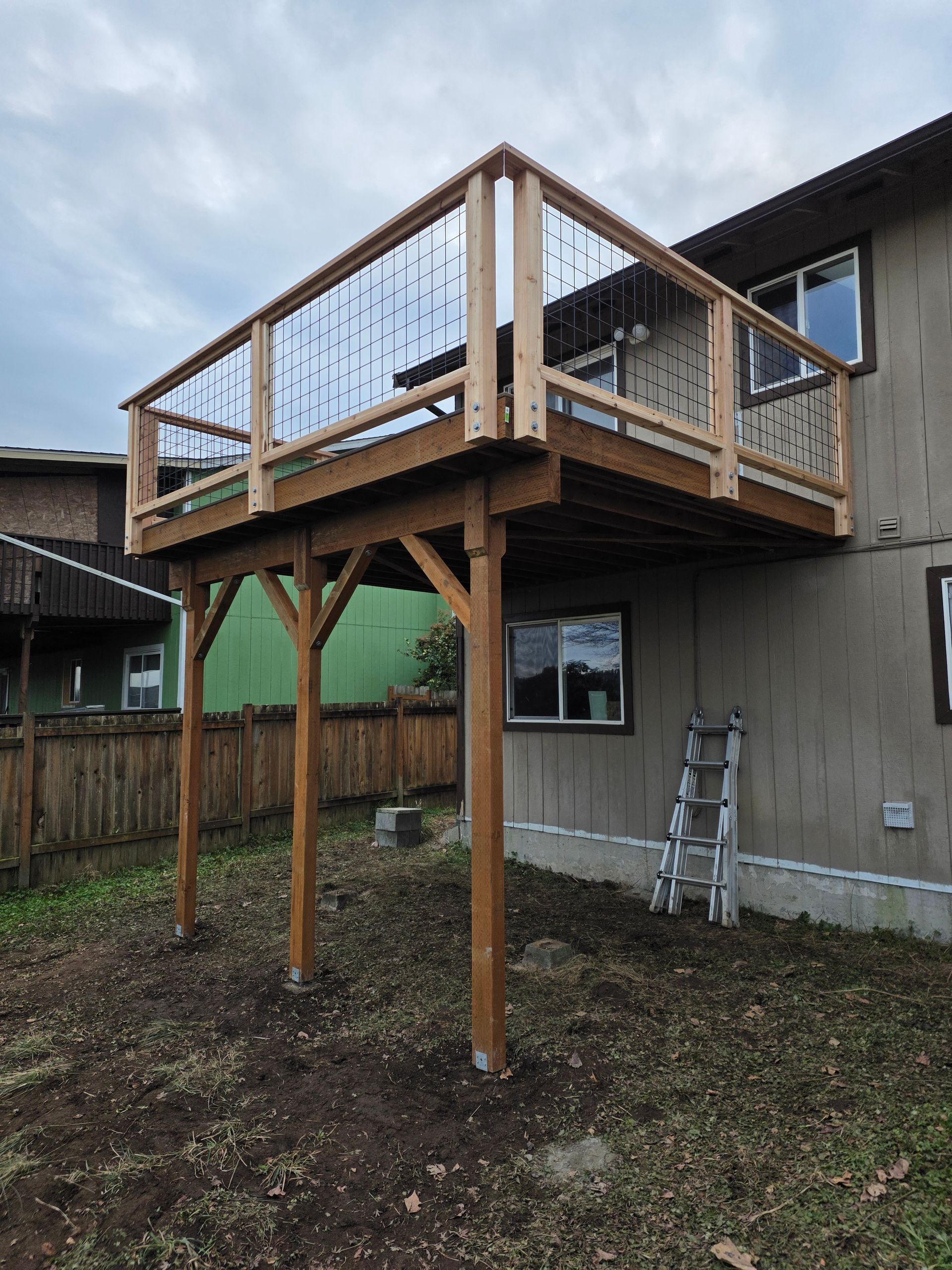 Elevated wooden deck attached to a house with metal railings, supported by posts.
