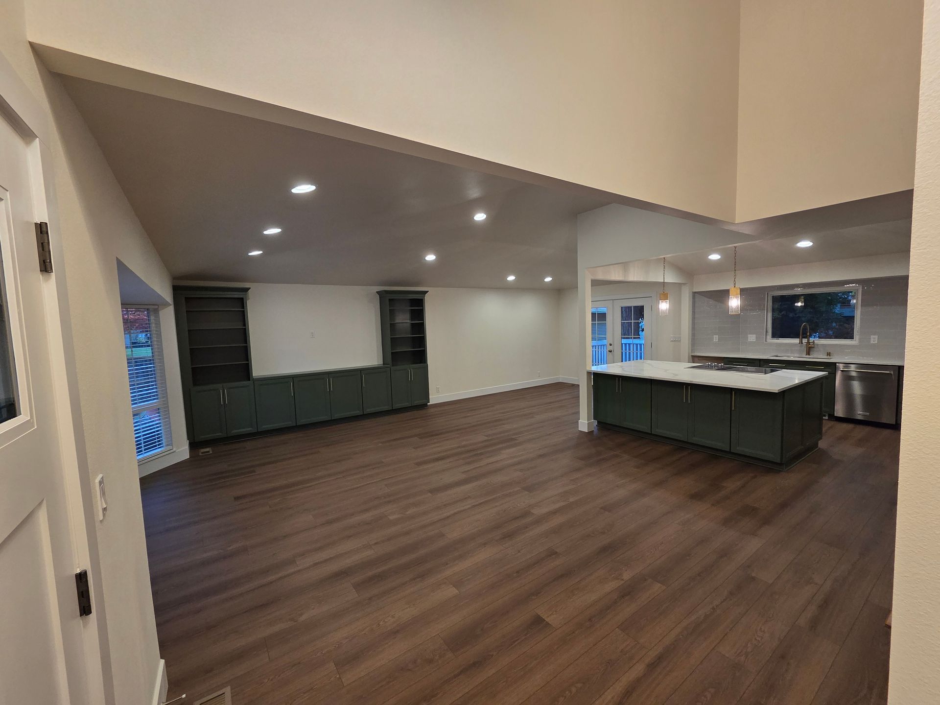 Open-concept kitchen and living area with dark wood floors, teal cabinets, and a kitchen island.