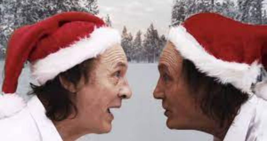Two men wearing santa hats are looking at each other in the snow.