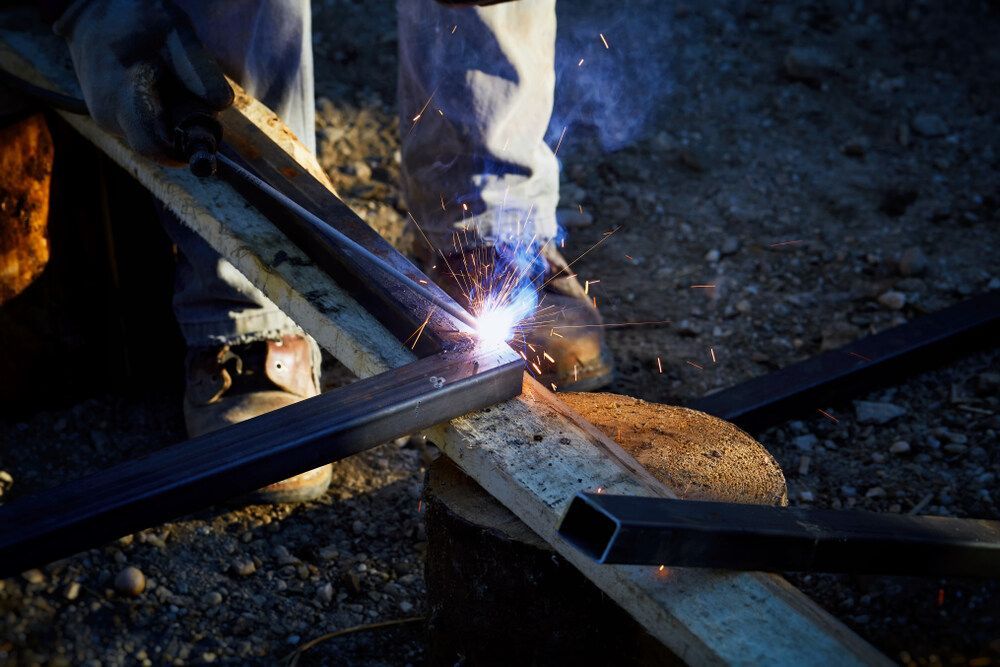 A Man Is Welding A Piece Of Metal On A Piece Of Wood — Dalrymple Sheet Metal In Garbutt, QLD