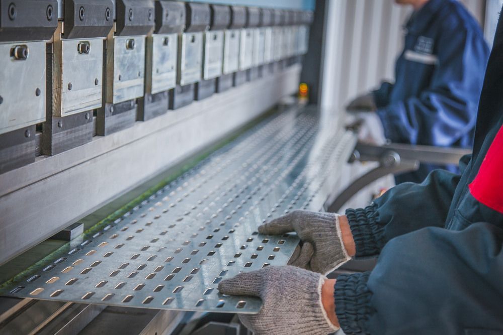 A Man Is Working On A Machine In A Factory — Dalrymple Sheet Metal In Mount Isa, QLD