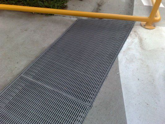A Metal Grate On A Sidewalk Next To A Yellow Railing — Dalrymple Sheet Metal In Townsville, QLD
