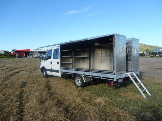 A White Truck Is Parked In A Grassy Field With Its Doors Open — Dalrymple Sheet Metal In Townsville, QLD